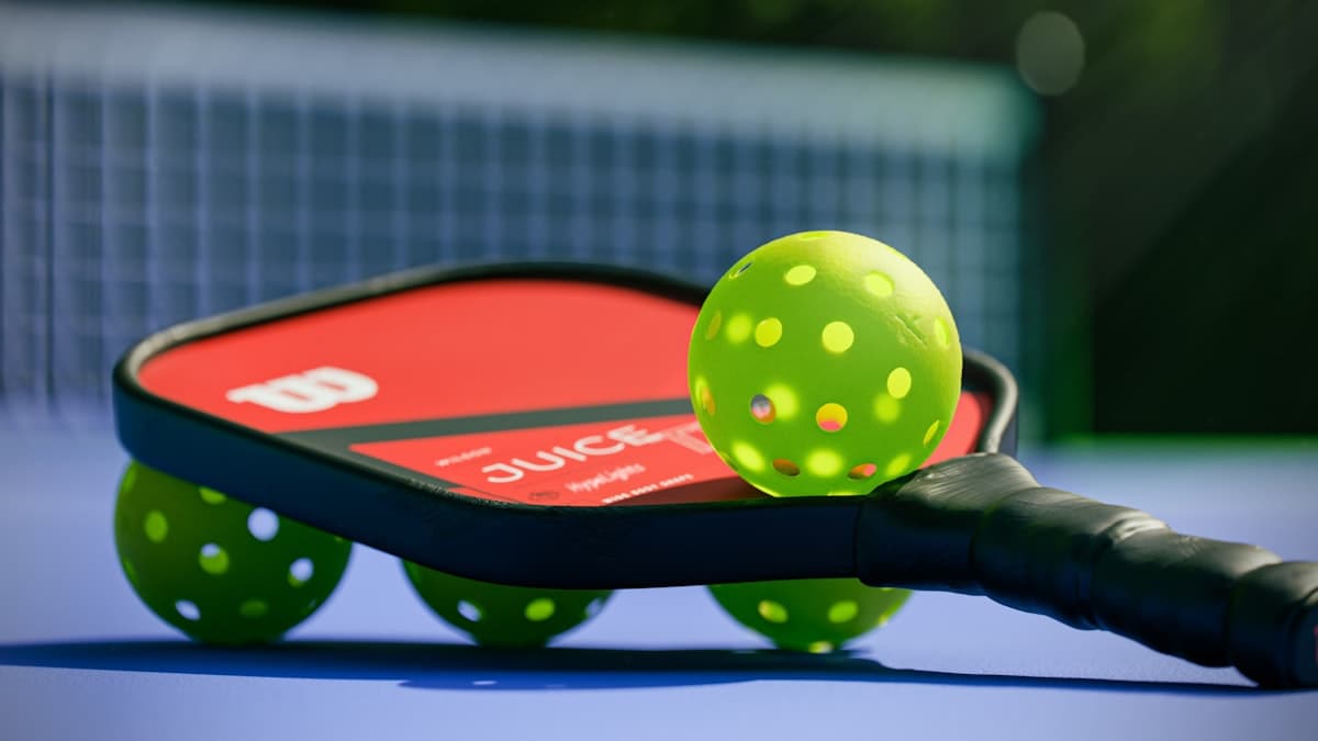 A pickleball paddle and ball on the court