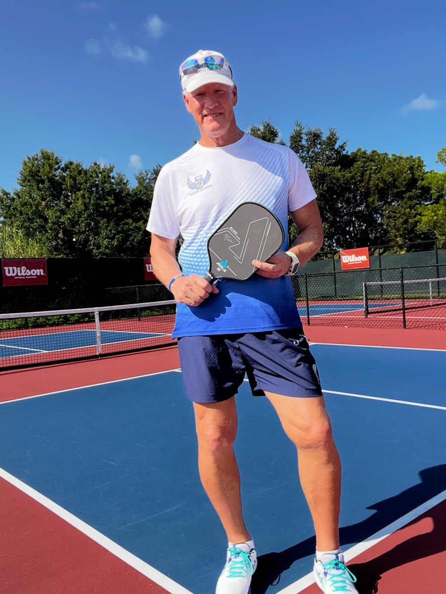 Coach Bruce holding a pickleball paddle on the court